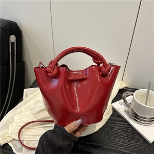 Fashionable red pleated bucket bag with knot handle and adjustable crossbody strap