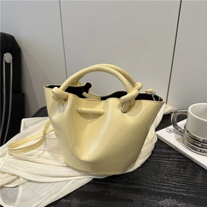 Chic pleated bucket bag in light yellow leather with knotted handle and shoulder strap