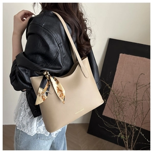 Detail of khaki tote bag featuring matte leather texture and decorative chain pattern scarf