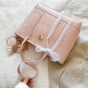 Pink faux leather tote bag with embossed cartoon patterns and a white lace bow detail