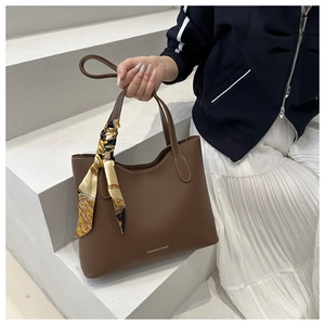 Détail d'un sac cabas en cuir marron avec poignée en foulard de soie et texte doré