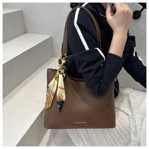 Détail d'un cabas marron foncé avec foulard en soie sur la bandoulière et lettrage doré