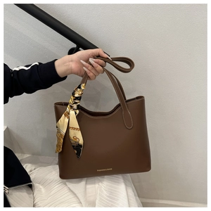 Détail du sac cabas en cuir marron foncé avec surpiqûres et nœud en foulard de soie floral