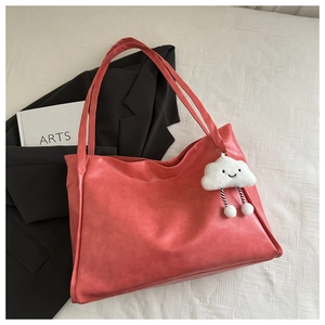 Dettaglio della borsa tote rosa corallo in pelle PU con un grazioso ciondolo a nuvola