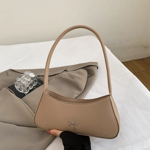 Chic beige hobo shoulder bag with a metal bow detail on a minimalist leather finish
