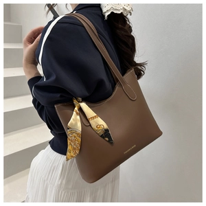 Détail d'un sac cabas en cuir marron avec un foulard en soie et des coutures blanches