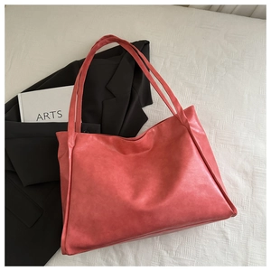 Dettaglio della borsa tote rosso corallo con trama in pelle e spalline resistenti