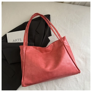 Vista dettagliata di una borsa tote rosso corallo capiente con trama in ecopelle opaca