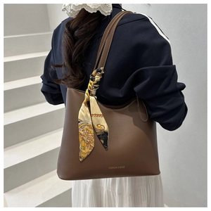 Detail of caramel leather tote bag with vintage scarf accessory and white stitching
