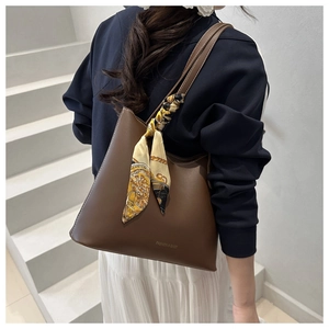 Détail d'un sac cabas en cuir marron foncé avec un foulard en soie vintage sur l'anse