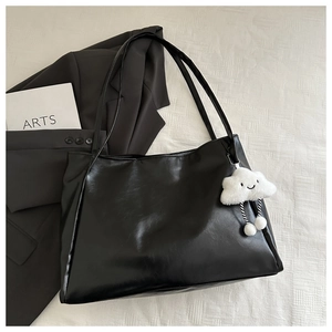 Dettaglio borsa tote in pelle PU nera con un simpatico ciondolo a forma di nuvola