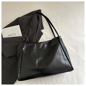 Vista dettagliata della borsa tote in ecopelle nera su tessuto bianco e blazer