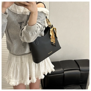 Détail d'un grand sac cabas noir en similicuir avec foulard en soie et logo doré chic