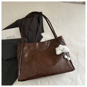 Dettaglio della borsa tote in pelle PU marrone caffè con ciondolo a nuvola bianca morbida