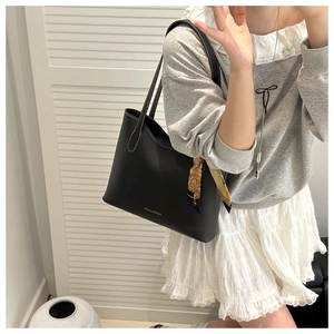 Détail d'un cabas en cuir noir avec surpiqûres blanches contrastées et foulard en soie