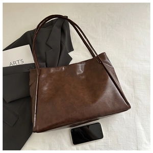 Dettaglio di una grande borsa tote marrone vintage con texture in pelle cerata e manici