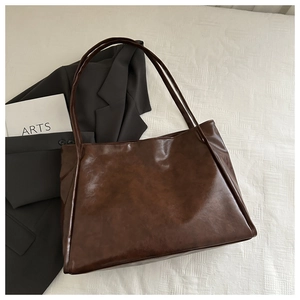Dettaglio della grande borsa tote in pelle marrone scuro su lino bianco per stile