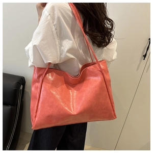 Dettaglio borsa tote rosa corallo con trama in pelle lucida e sottili spalline da spalla
