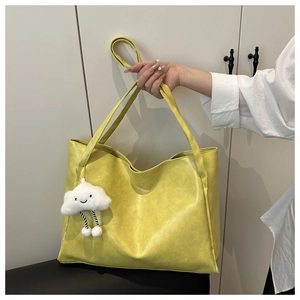 Dettaglio della borsa tote gialla con texture in pelle e ciondolo a nuvola di peluche