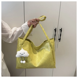 Dettaglio della borsa tote in pelle gialla con texture e ciondolo a forma di nuvola