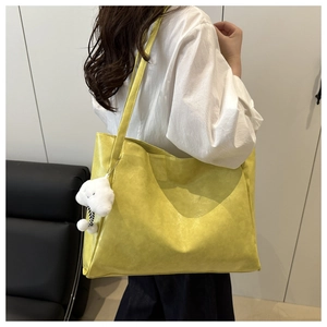 Modella che indossa una grande borsa tote gialla con ciondolo a forma di nuvola bianca