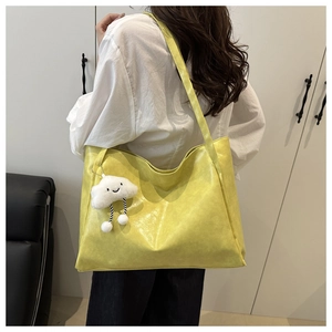 Detailed texture of vibrant yellow tote bag with a cute white cloud plush pendant charm