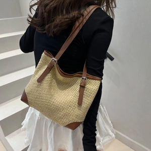Contrast color straw tote bag with brown leather handles and base for beach outings