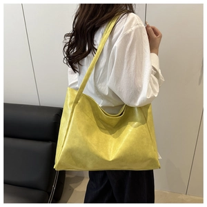 Dettaglio di una grande borsa tote in pelle giallo brillante indossata da una modella