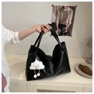 Dettaglio borsa tote in pelle nera con ciondolo a nuvola di peluche bianca elegante