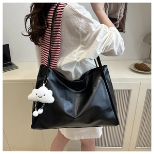 Dettaglio di una borsa tote grande in finta pelle nera con ciondolo a nuvola per tutti i giorni