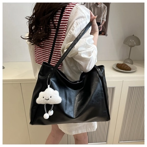 Dettaglio borsa tote nera in pelle PU con un ciondolo a forma di nuvola bianca morbida