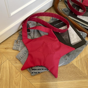 Sac à bandoulière rouge en forme d'étoile en toile sur un fond en bois de style tendance