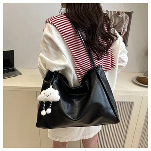 Dettaglio della borsa tote nera con ciondolo a nuvola e texture in pelle premium