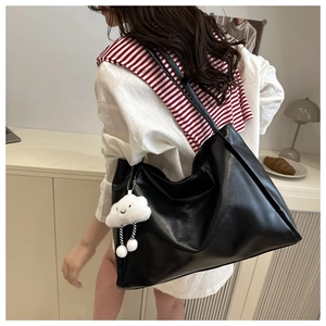 Detail of black leather tote bag with cloud charm accessory in a lifestyle interior