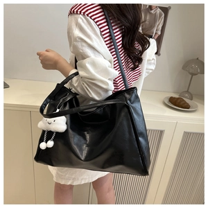 Detailed macro view of large black shiny PU leather tote bag with cloud plush charm detail