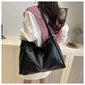 Borsa tote nera minimalista capiente con trama in pelle indossata da una modella