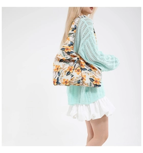 Detailed close-up of large decorative bow and floral print on a canvas tote shoulder bag