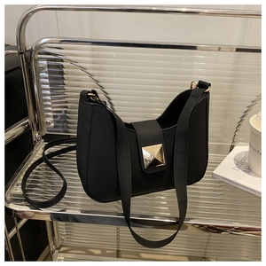 Detail of minimalist black matte leather crescent bag featuring a gold pyramid metal clasp