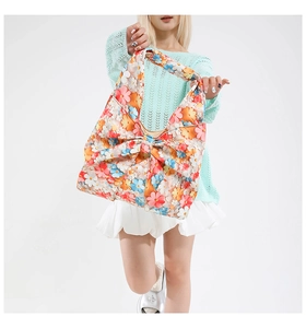 Floral print tote bag with a large bow shown on model with light blue top and white skirt