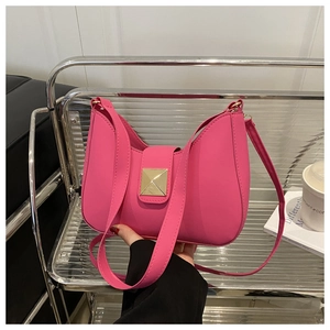 Detail of a bright pink crescent shoulder bag with golden buckle on a modern chair
