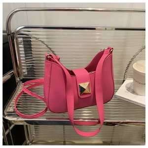 Detail view of pink crescent shoulder bag featuring a gold pyramid stud on matte leather