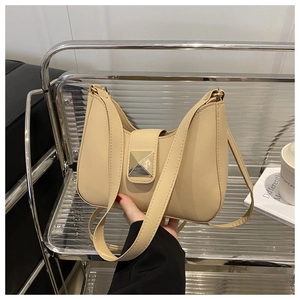 Detail of beige crescent underarm bag with a golden square rivet buckle on a metal rack