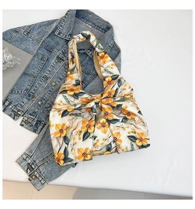 Detailed view of floral silk fabric handbag featuring a large bow and orange flower print
