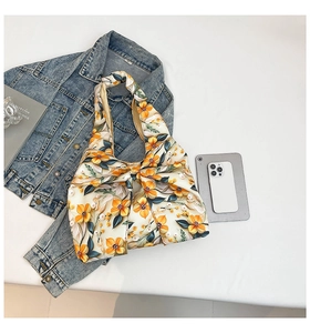 Detailed view of yellow floral pattern on satin shoulder bag with knot bow handle style