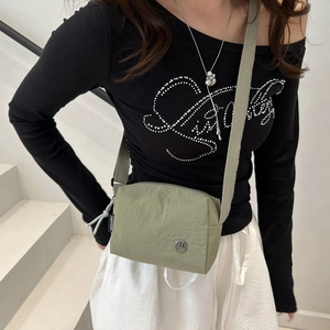 Dettaglio della borsa a tracolla in nylon verde oliva con stemma M in metallo