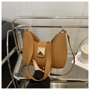Detailed close-up of brown crescent bag with a decorative gold square buckle and fine strap