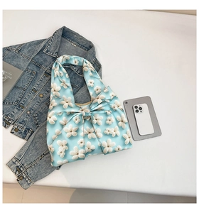 Detail of light blue satin tote bag with white 3D floral accents and large bow design