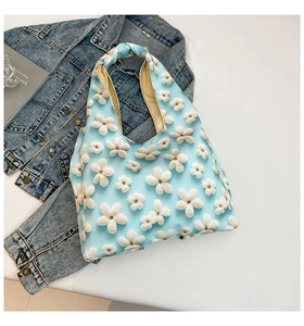 Close-up of a light blue fabric tote bag with 3D white crochet flower decorations