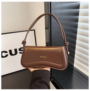 Detail view of smooth dark brown PU leather bag with XM & BAGS logo and decorative knot