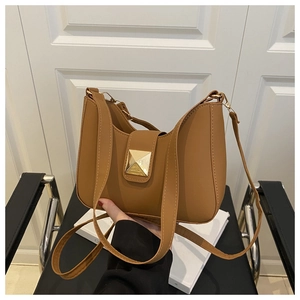 Detail of camel leather crossbody bag with bold gold buckle and adjustable strap